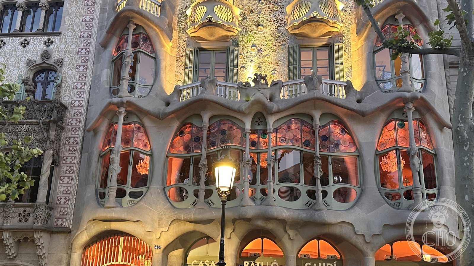 Casa Batllo at dusk, its bone-like balconies and mosaic facade lit from within